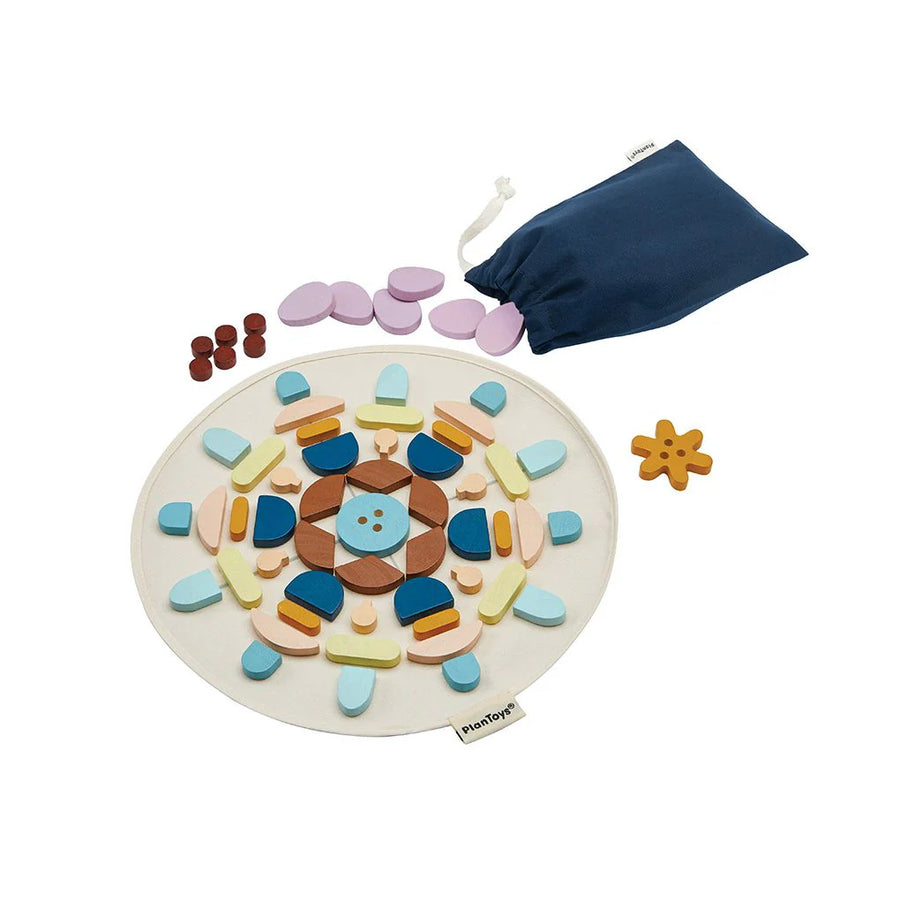 PlanToys mandala pieces arranged in a circular pattern beside a blue storage bag.
