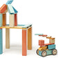Tegu Sunset blocks arranged into a house on stilts beside a small wheeled vehicle.