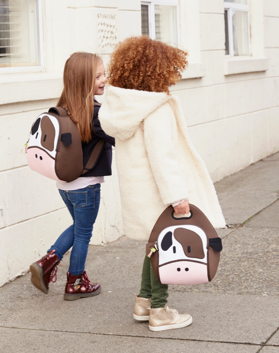 Two children carrying brown-and-white Dabbawalla Holy Cow lunch bags.