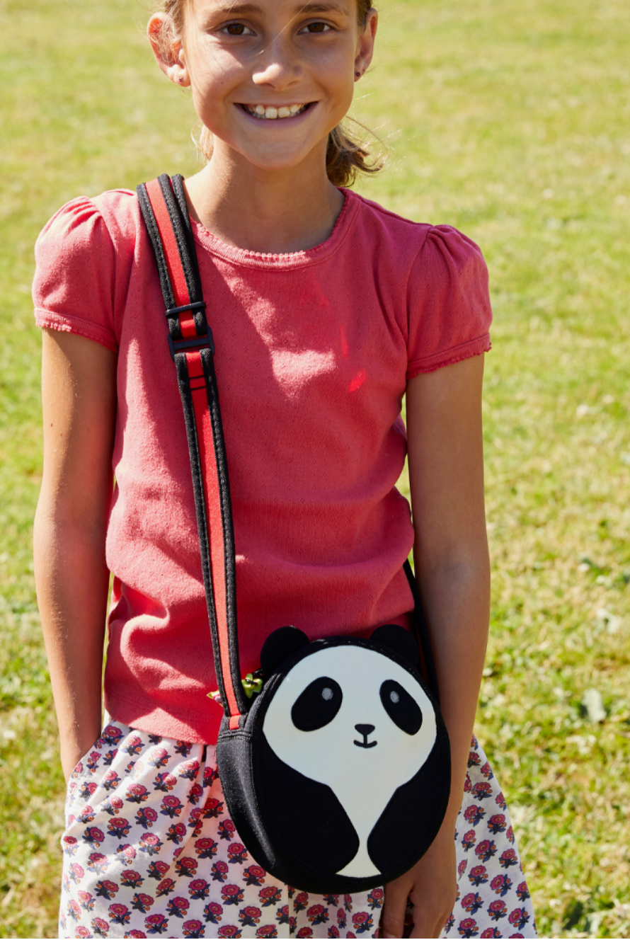 Child wearing a round black-and-white Dabbawalla Panda Bear crossbody bag.