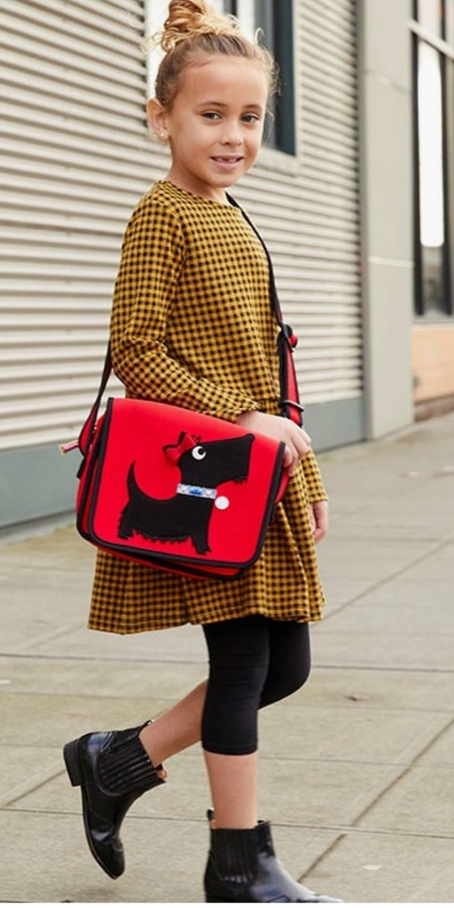 Child carrying a red Dabbawalla crossbody bag with a black Scottie dog design.