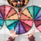 Child reaching toward circular patterns made from pastel CONNETIX triangular tiles.